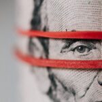 Closeup of rolled United States five dollar bills tightened with red rubber band