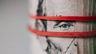 Closeup of rolled United States five dollar bills tightened with red rubber band