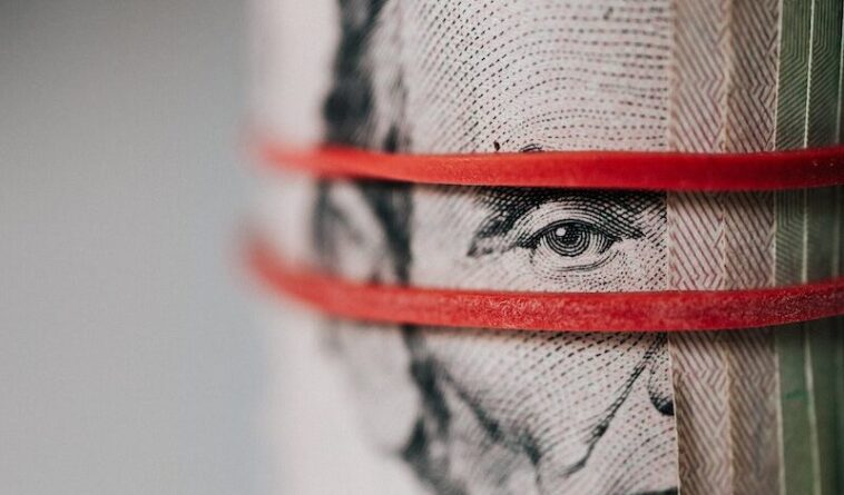 Closeup of rolled United States five dollar bills tightened with red rubber band
