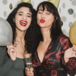 Cheerful women with balloons among confetti