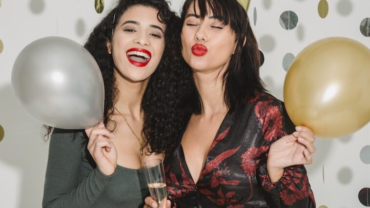 Cheerful women with balloons among confetti