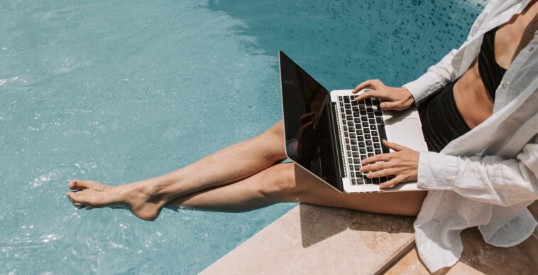 Woman Sitting on Poolside Using Laptop