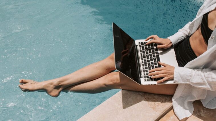 Woman Sitting on Poolside Using Laptop