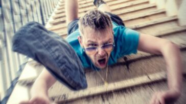 man in blue t-shirt and blue denim shorts sitting on concrete stairs during daytime