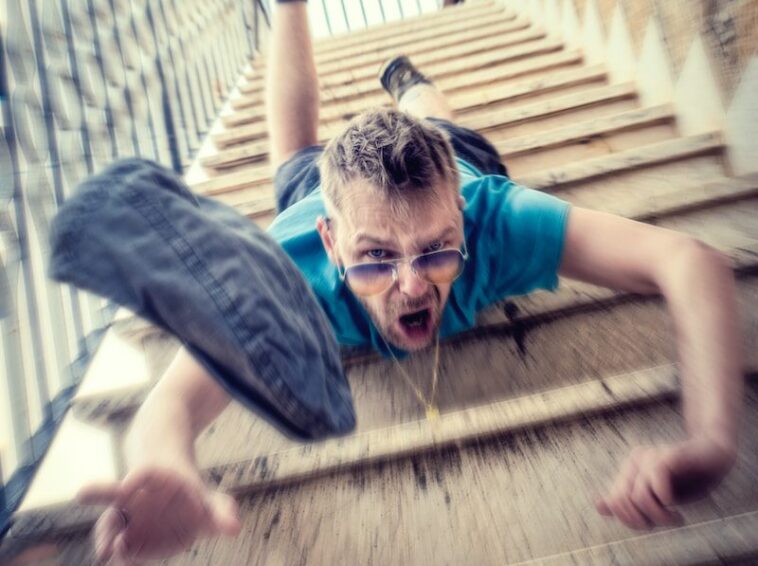 man in blue t-shirt and blue denim shorts sitting on concrete stairs during daytime