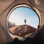a man standing in a tent looking out into the distance