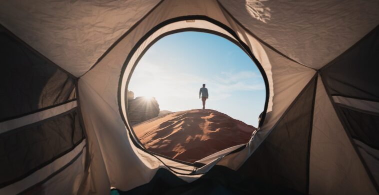 a man standing in a tent looking out into the distance